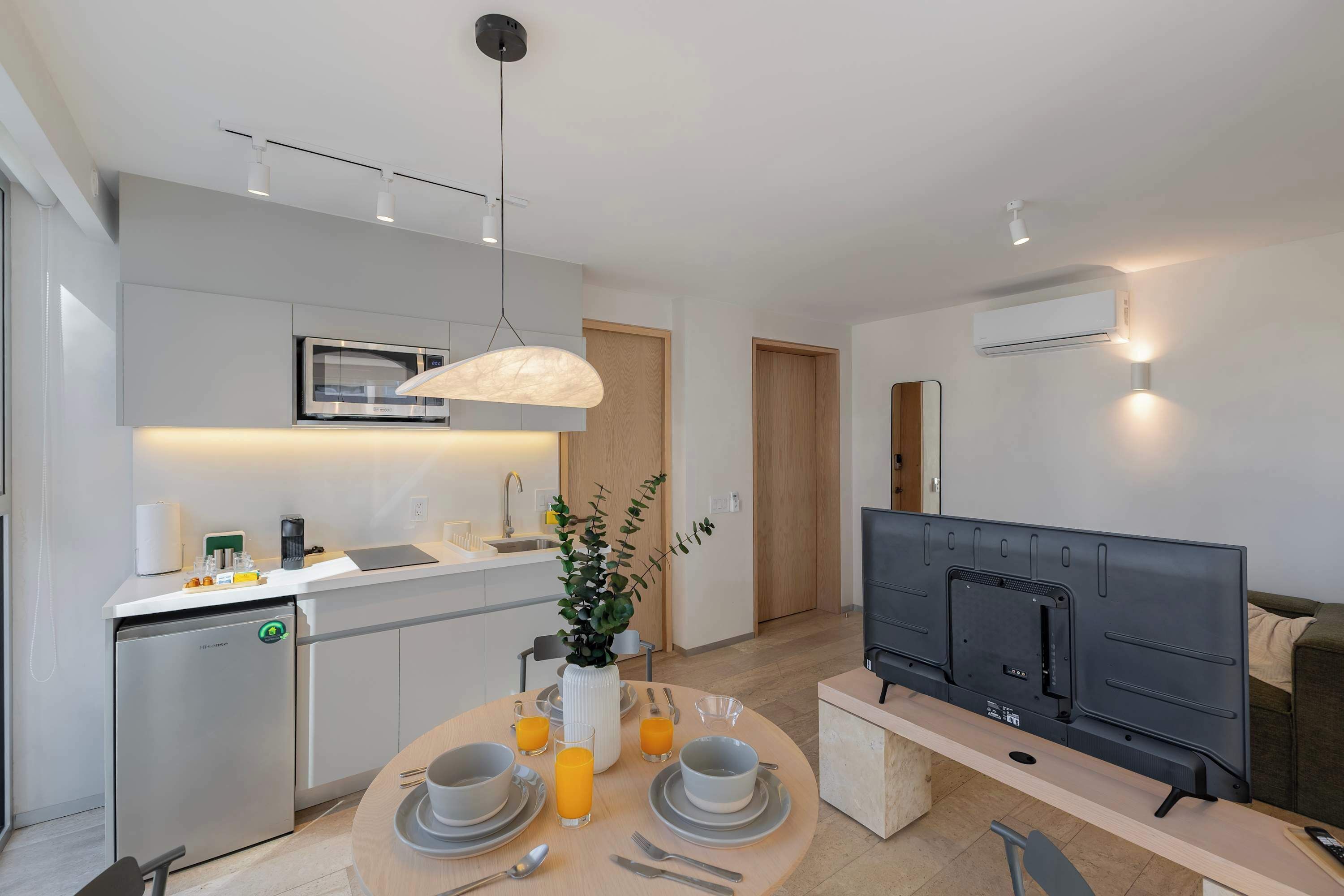 A modern kitchen with a dining area, a built-in oven, and a flat-screen TV.