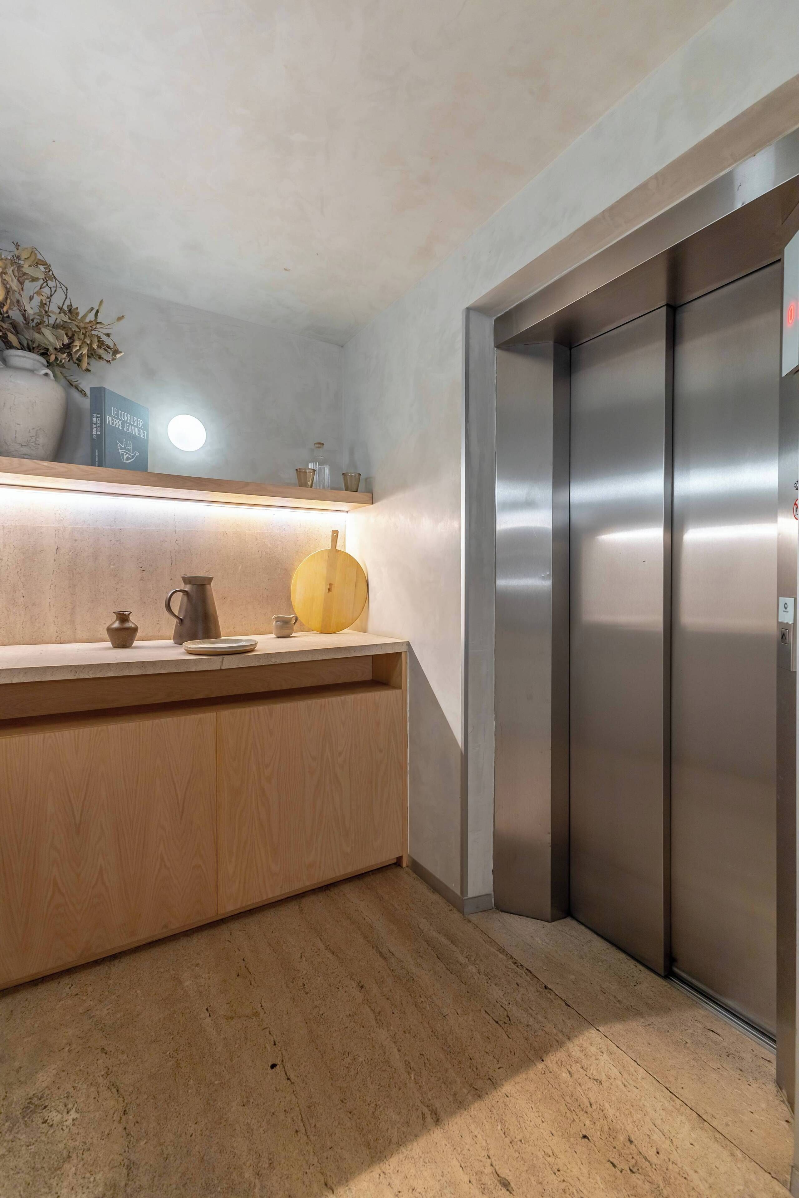 A modern kitchen with a wooden countertop, a yellow pumpkin, and a stainless steel elevator.