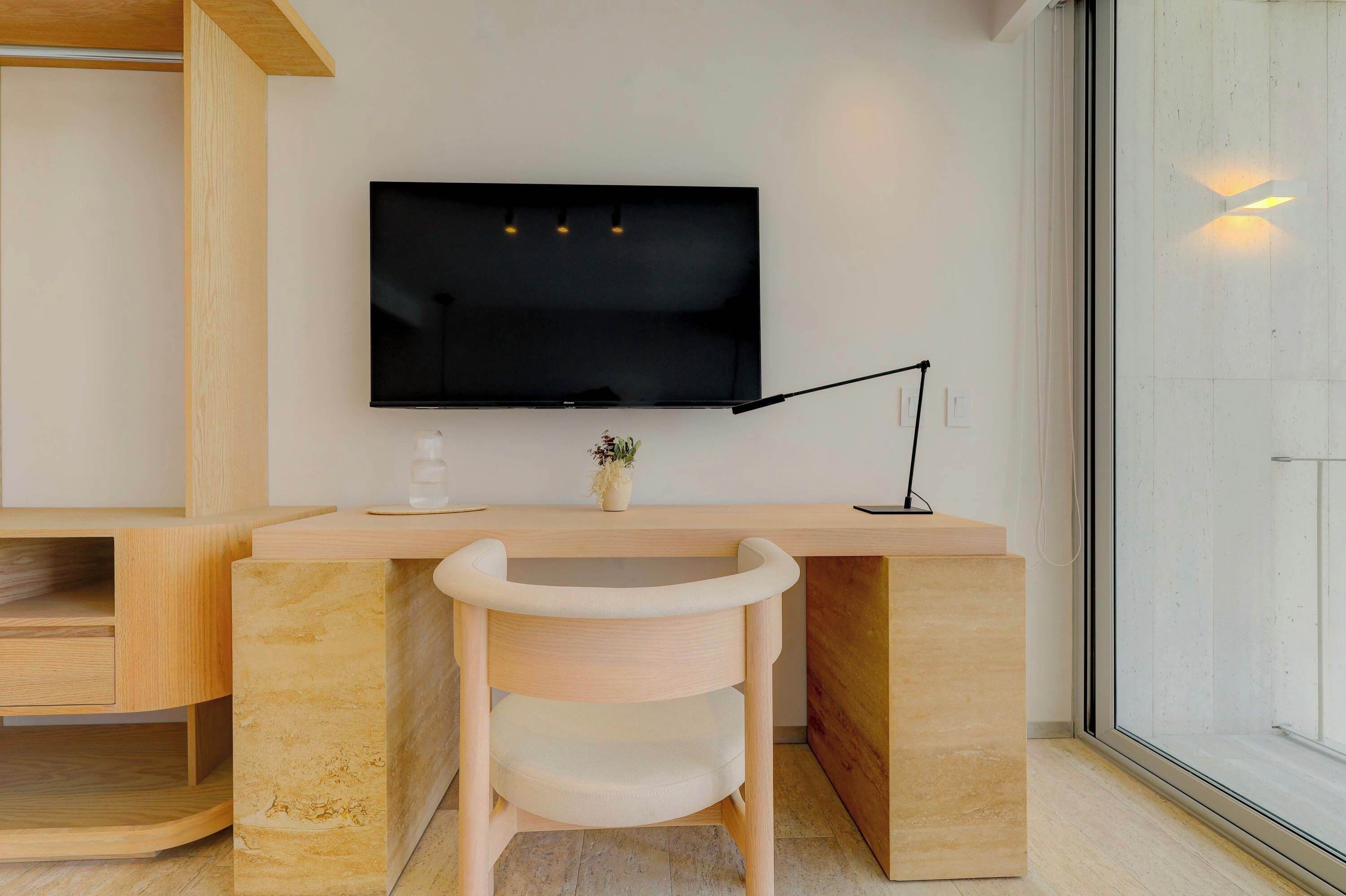 Een moderne werkruimte met een flatscreen televisie, een bureau, een stoel en een raam.