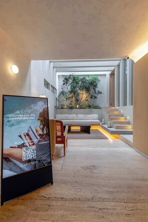 Un interior moderno con una televisión de pantalla plana mostrando un anuncio, un sofá, una mesa de comedor y una escalera que sube a un nivel superior.