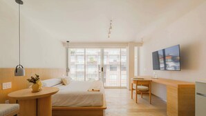 Camera d'albergo moderna con un letto, una scrivania, una sedia, una TV e ampie finestre.