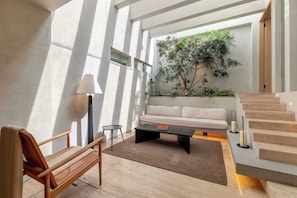 Ein modernes Wohnzimmer mit einer Couch, einem Couchtisch, einer Lampe, einer Bank und einer Treppe.