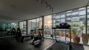 Una palestra con attrezzi per l'allenamento, ampie finestre e piante in vaso.