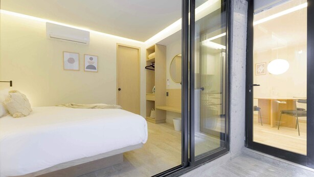 A hotel room with a bed, a sliding glass door leading to a bathroom, and a visible shower area. - Capitalia Aristoteles Polanco (Ciudad de México)