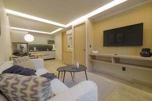 A modern living room with a sofa, coffee table, and a flat-screen TV mounted on the wall.
