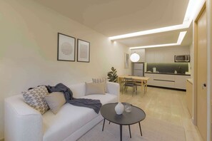 A modern living room with a sofa, a small table, and a kitchen area in the background.