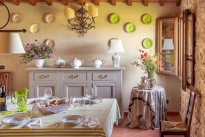 A dining area with a table set for four, a pitcher, and a basket of bread. There are plates and a vase with flowers on the wall. - Villa Saffo: A charming three-story villa surrounded by meadows and by green hills, with Free WI-FI. (Bucine)