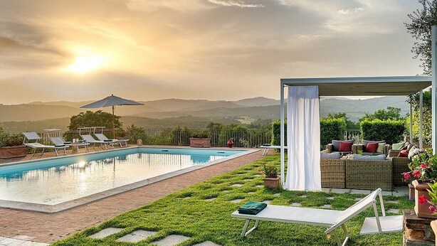 A swimming pool with lounge chairs and a covered seating area, surrounded by a well-maintained lawn and potted plants. - Villa Saffo: A charming three-story villa surrounded by meadows and by green hills, with Free WI-FI. (Bucine)