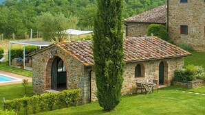 A stone building with a tiled roof, a covered outdoor seating area, and a well-maintained lawn. - Villa Saffo: A charming three-story villa surrounded by meadows and by green hills, with Free WI-FI. (Bucine)