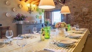 A dining area with a long table set for a meal, surrounded by stone walls and wooden beams. - Villa Saffo: A charming three-story villa surrounded by meadows and by green hills, with Free WI-FI. (Bucine)