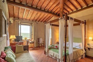 A bedroom with a four-poster bed, a television, a desk with a lamp, and a chair. - Villa Saffo: A charming three-story villa surrounded by meadows and by green hills, with Free WI-FI. (Bucine)