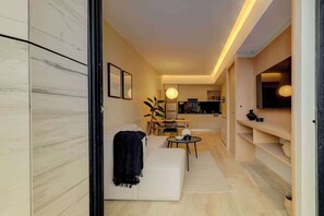 A modern living room with a sofa, a dining table, and a kitchen area in the background.