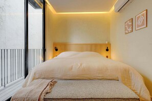 Une chambre à coucher avec un lit, une fenêtre donnant sur un beau paysage et deux appliques murales.
