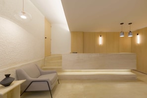 A reception area with a reception desk, a waiting chair, and a staircase.