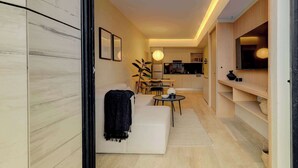 Una sala de estar moderna con un sofá, una mesa de comedor y una cocina al fondo.