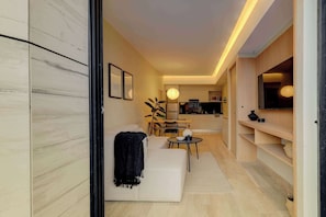 A modern living room with a sofa, a dining table, and a kitchen area in the background.