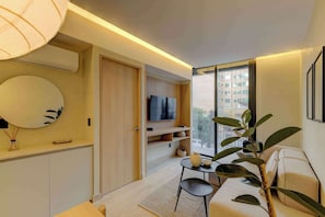 A modern living room with a sofa, a TV, a dining table, and a large window.