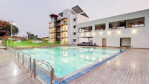 Un hotel moderno con piscina, varios pisos y paneles solares en el techo.
