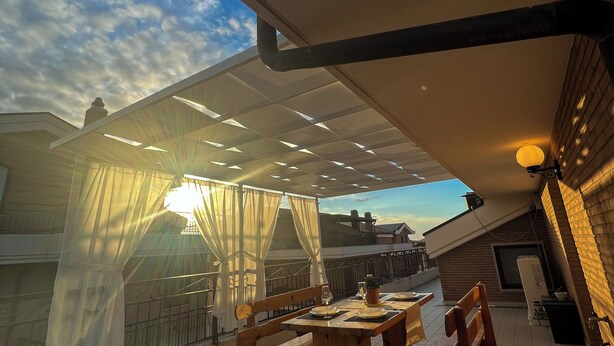 A covered outdoor dining area with a table and benches, a pergola with curtains, and a view of the sky. - beb dragonara (Torremaggiore)