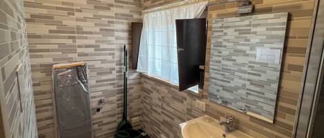 Un baño con salpicadero de azulejos, un inodoro, un lavamanos y un espejo.