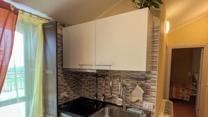 A modern kitchen with a black stove, stainless steel sink, and wooden cabinets. - beb dragonara (Torremaggiore)