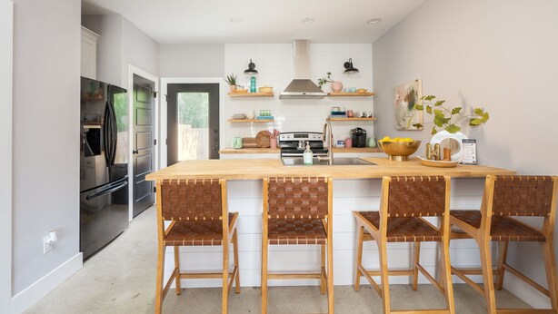 A modern kitchen with a central island, bar stools, and a refrigerator. - HowdyHouse: Designer Townhouse in Historic FOODIE  Bryan Minutes to Kyle Field (Bryan)