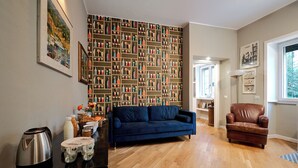 Ein Wohnzimmer mit einem blauen Sofa, einem Bücherregal, einem Couchtisch und einem braunen Ledersessel.