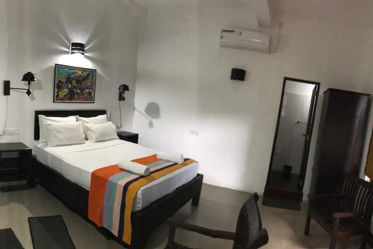 A bedroom with a bed, bedside tables, a desk, a chair, and a mirror.