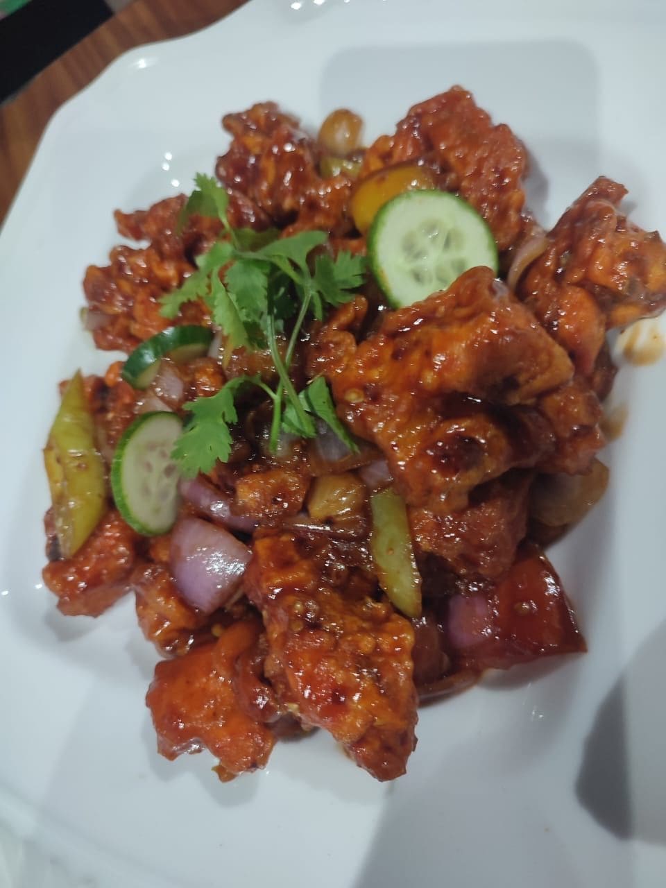 A dish with meat, vegetables, and a garnish on a white plate.