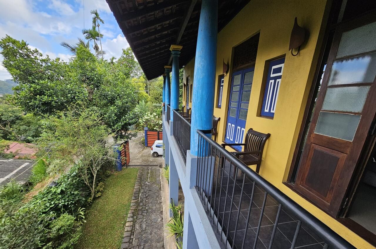 Un edificio amarillo con pilares azules y un balcón.