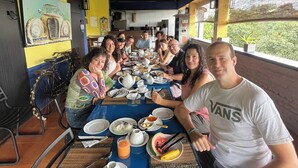 Un groupe de personnes est réuni autour d’une table, où se trouvent divers plats et boissons.