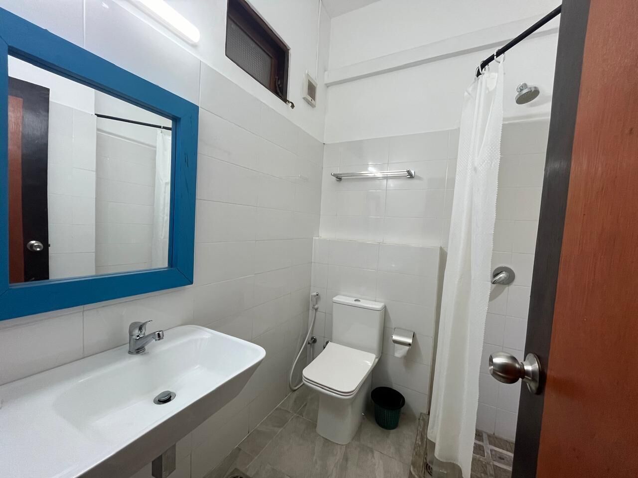 Un baño con lavamanos blanco, inodoro y zona de ducha.