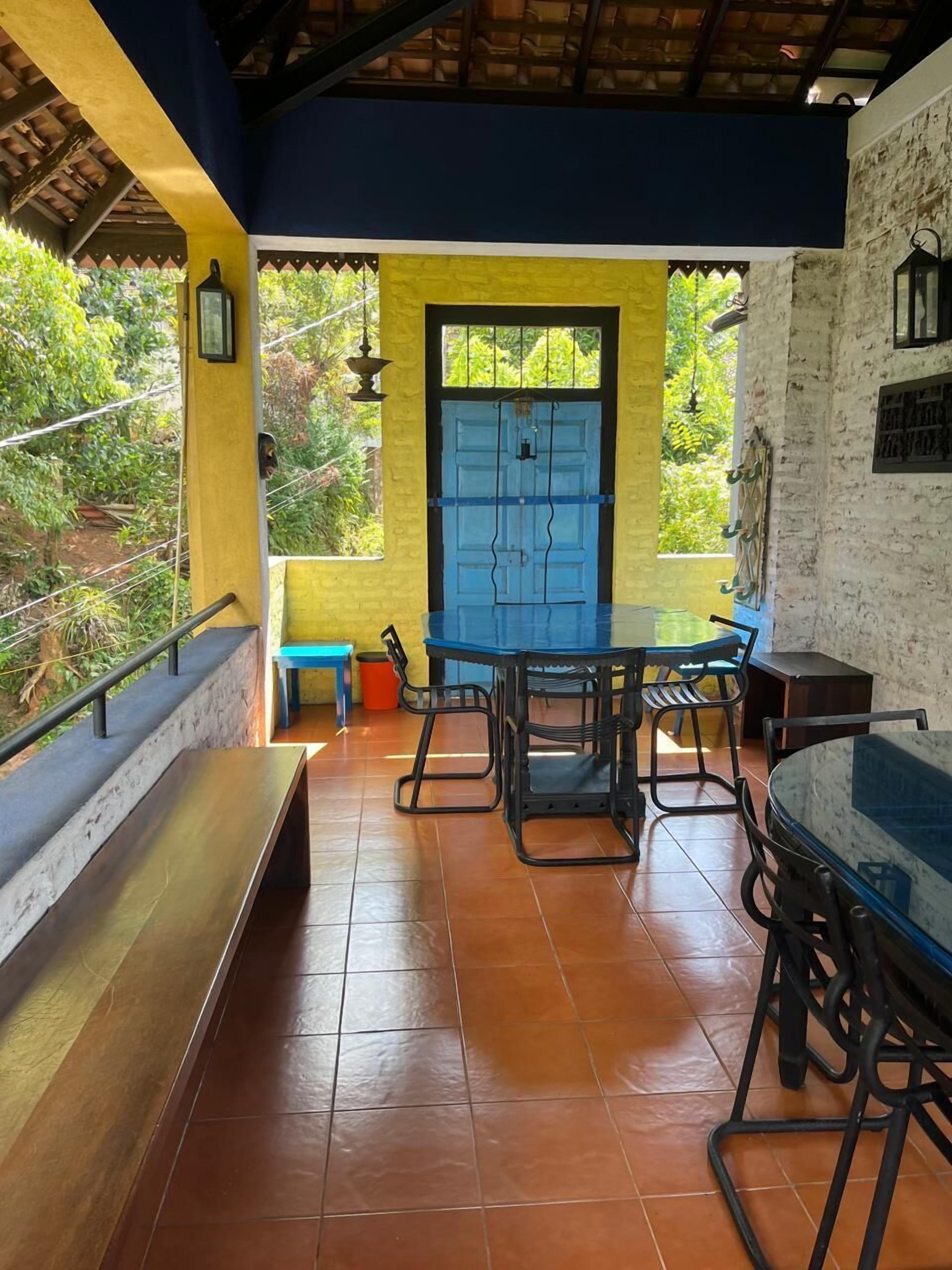 A covered patio area with a blue door, a table with chairs, and a bench.