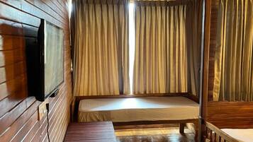 Ein Zimmer in einer Holzhütte mit Etagenbett, einem kleinen Tisch mit Wasserkocher und einem an der Wand befestigten Fernseher.