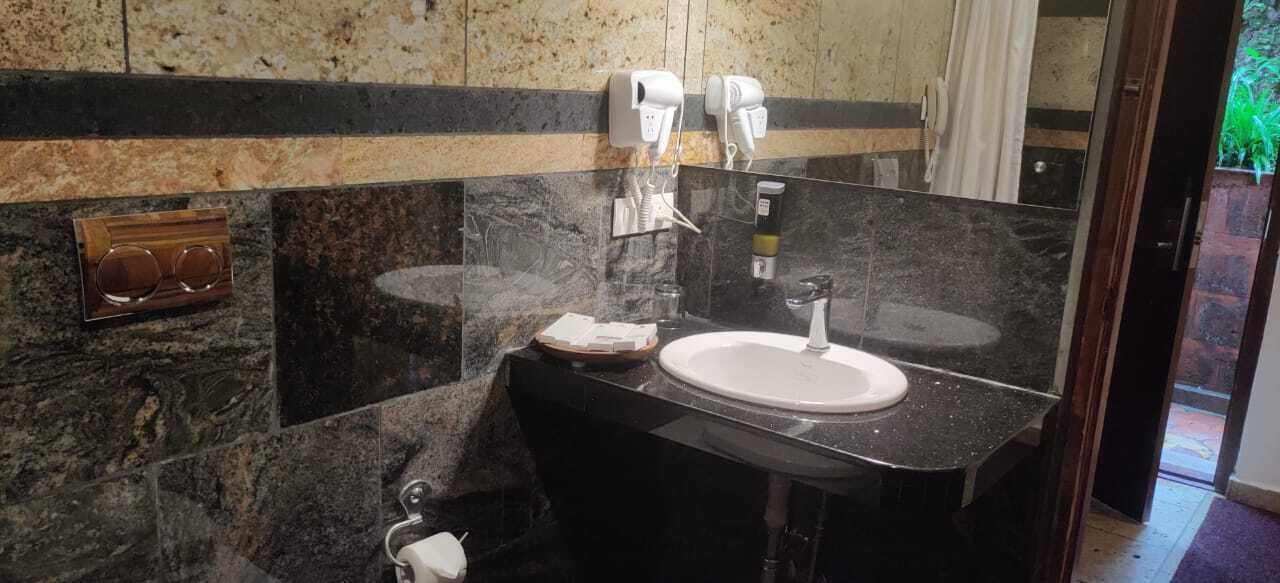 Un bany amb un mànec de marbre negre, dos assecagats de mans blancs i un mirall.