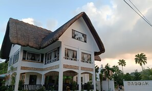 A two-story house with a thatched roof, multiple windows, and a sign reading "BAGGAK". - Baggak Hotel and Restaurant by SMS Hospitality (Sanchez-Mira)