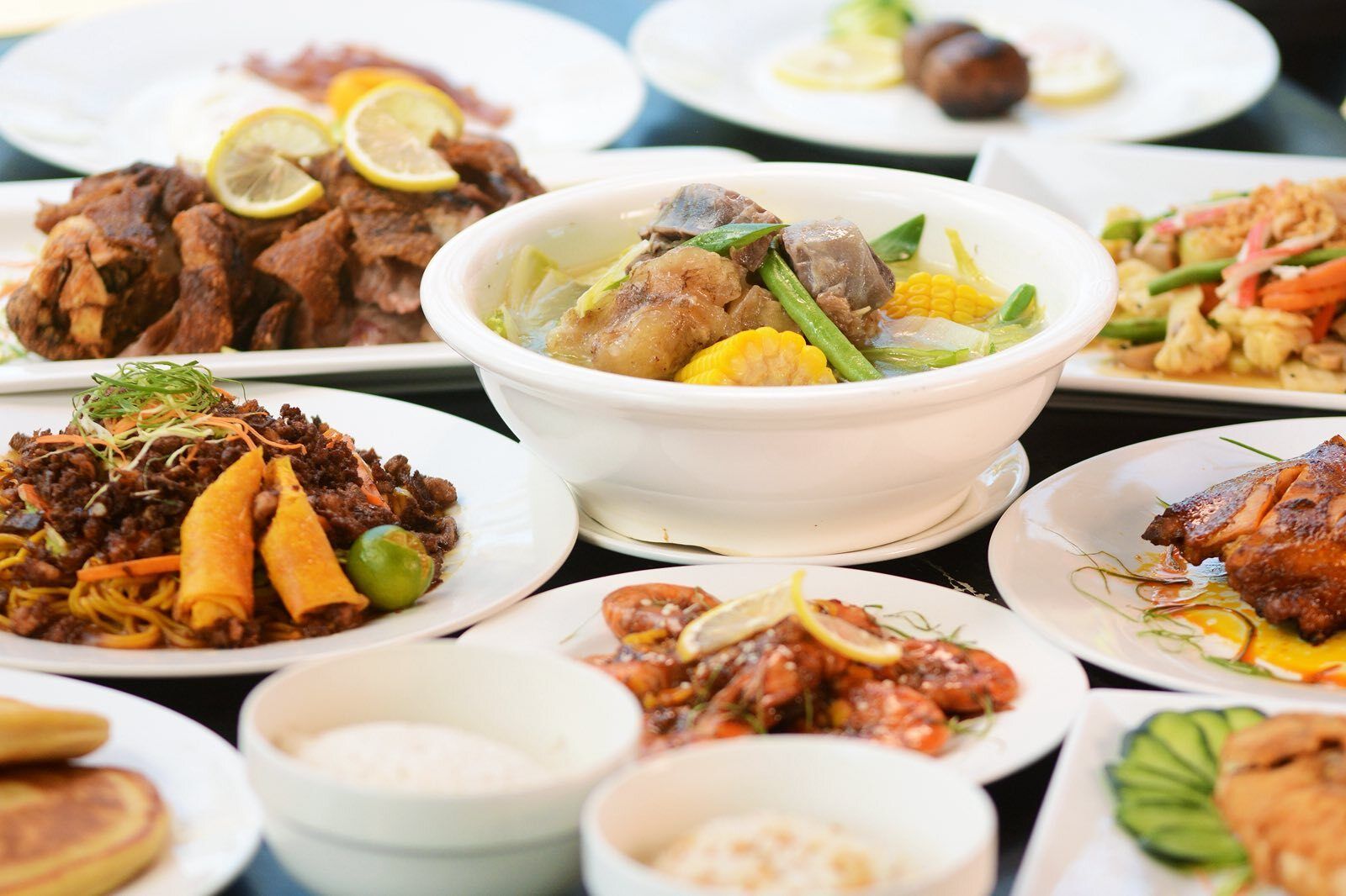 Une variété de plats sont disposés sur la table, notamment un bol de soupe contenant des légumes et de la viande, ainsi que d’autres assiettes avec différents types d’aliments.