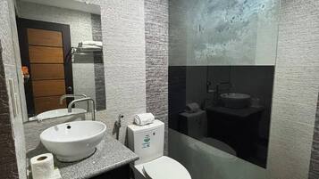 Un bany modern amb un mirall gran, dues safates, un vàter i una zona de dutxa.