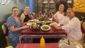 A dining area with a red table, various dishes, and a yellow condiment bottle.