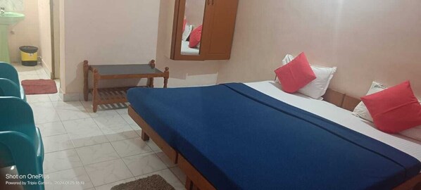 A room with a bed, a wooden bench, a small table, and a mirror on the wall. - GOD'S OWN VILLA (Neyyattinkara)