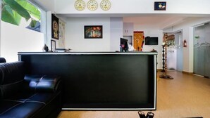 A reception area with a black reception desk, a black leather couch, and a wall clock.