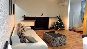 En stue med sofa, sofabord, fjernsyn og juletræ.