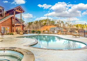 A log cabin-style building with a pool area, including a small hot tub and a fenced deck. - Golfing Dreams (Pigeon Forge)