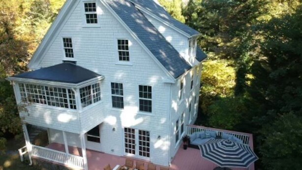 A two-story house with a covered patio and a dining area. - Quissett Landing | Sleeps 12 | Walk to The Knob (Falmouth)