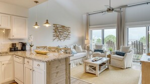 A spacious kitchen with white cabinets, a granite countertop, and a dining area with a white table and chairs.