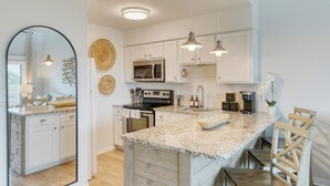 A modern kitchen with white cabinetry, granite countertops, and stainless steel appliances.