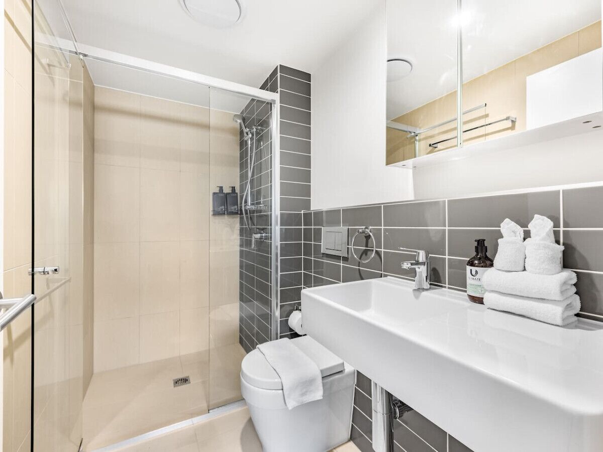 Une salle de bain moderne avec une douche à parois de verre, un lavabo blanc et des toilettes.