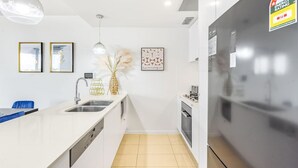 A modern kitchen with white cabinetry, a stainless steel refrigerator, and a tiled floor.