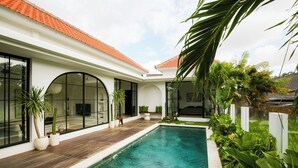 Una casa moderna con piscina, ventanas amplias y techo de tejas.