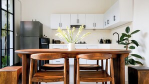 Una cocina moderna con armarios blancos, un refrigerador de acero inoxidable, una cafetera y una planta en maceta.